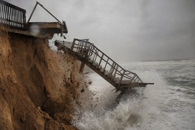 A wooden beach staircase ending abruptly over an eroded drop
