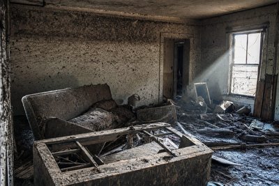 A flood-damaged living room interior with a visible waterline on the wall