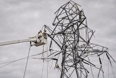 A utility line crew repairing a damaged transmission tower against an overcast sky after a storm (AI-generated image)