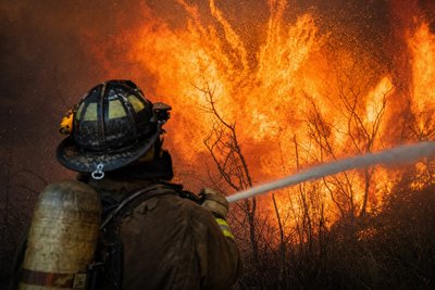 A firefighter defending a residential treeline from wildfire